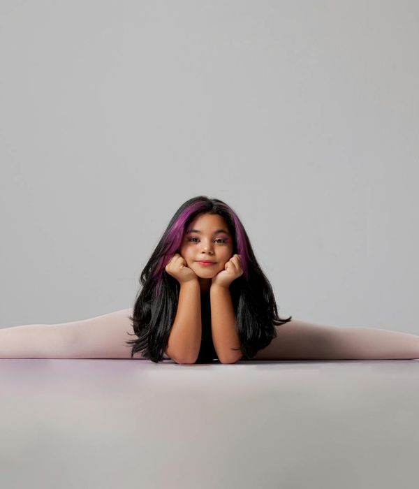 Woman in a calm yoga pose in a studio with purple ambiance.